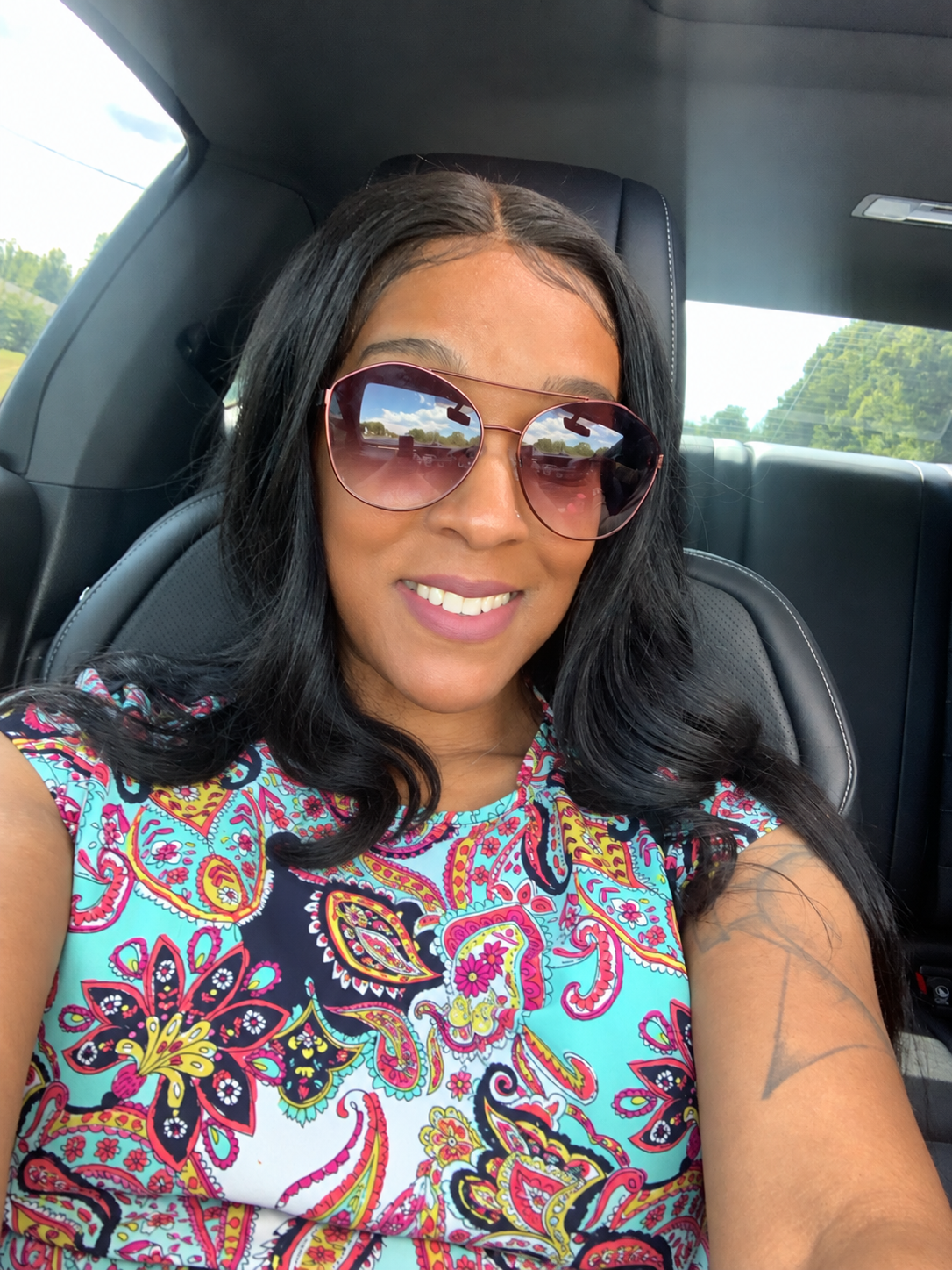 Kirstie smiling in sunglasses and a colorful floral top